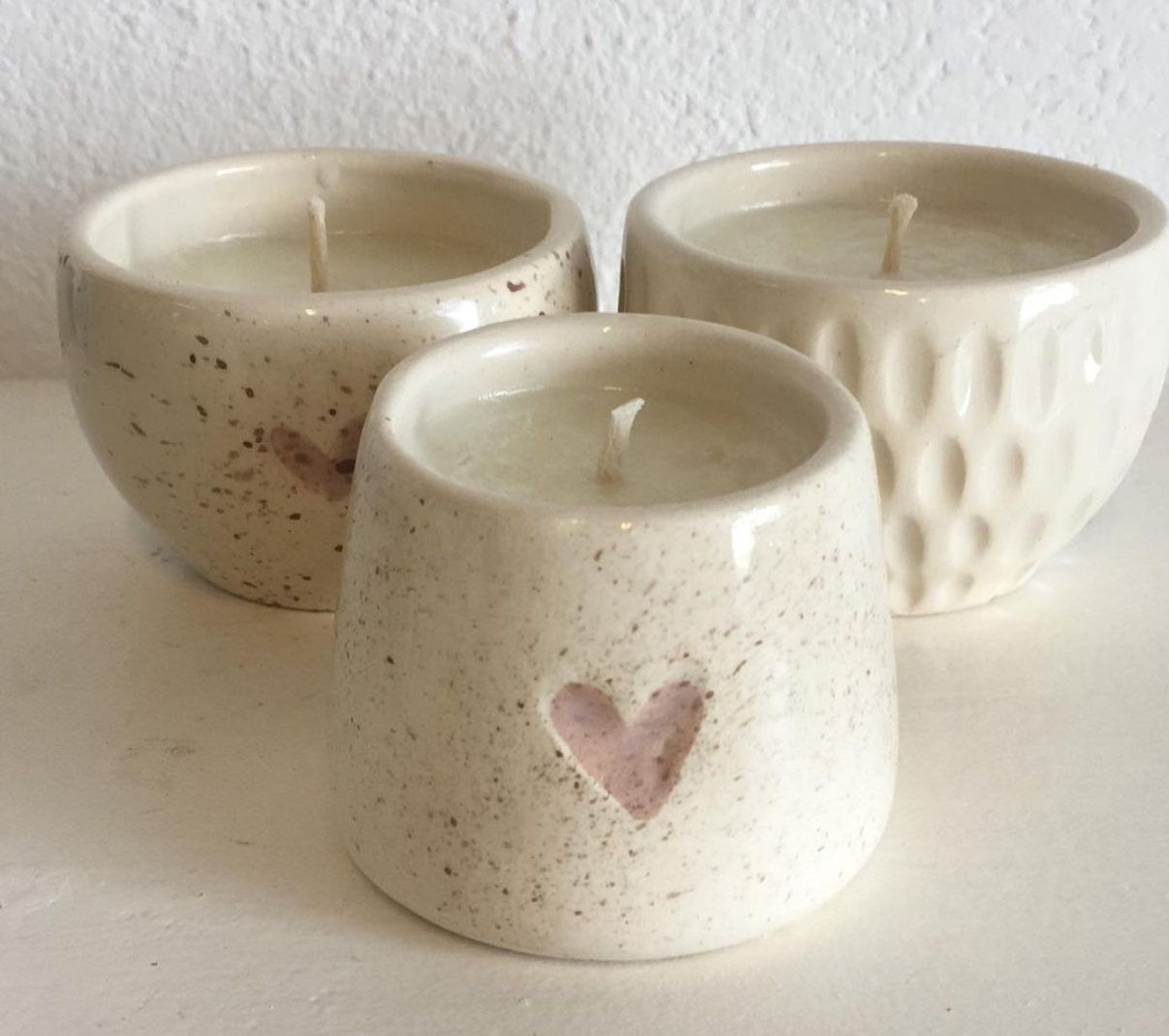 Velas de cera de soja en recipientes de cerámica artesanal de color blanco y detalles en negro y rosa